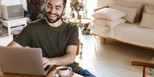 man laughing at home on laptop