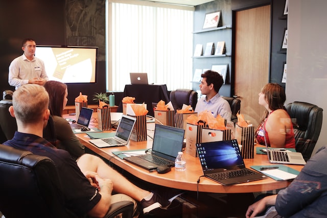 coworkers in meeting room with laptops