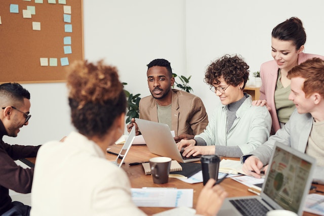 Man wearing brown suit meeting with team