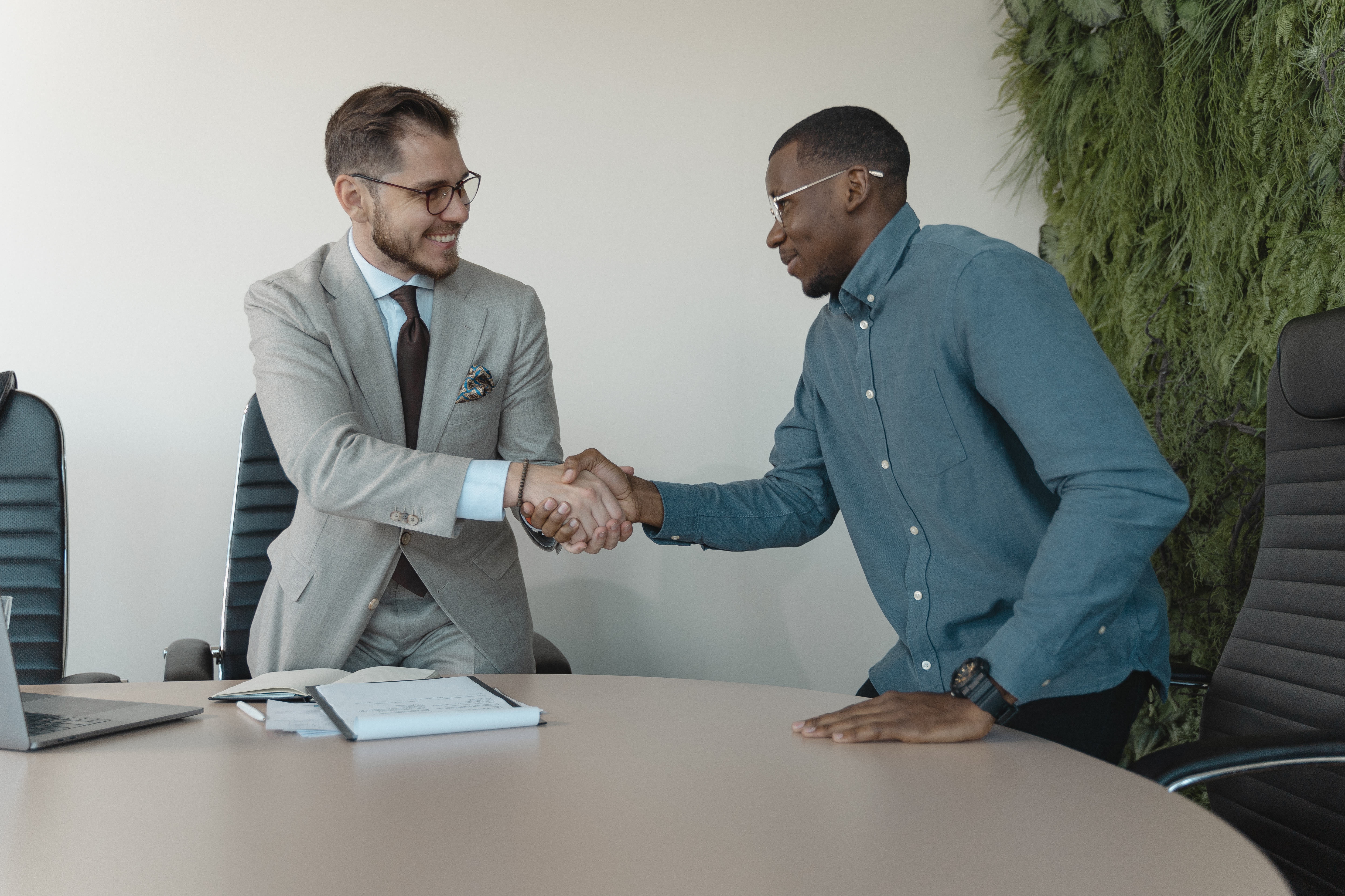 man in blue shirt shaking hands with man in grey suit