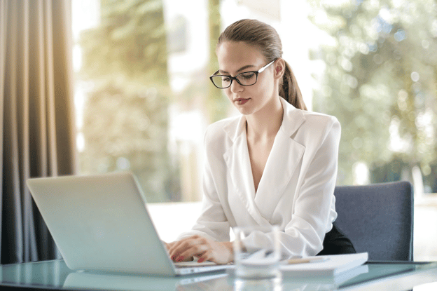 woman with glasses looking at laptop