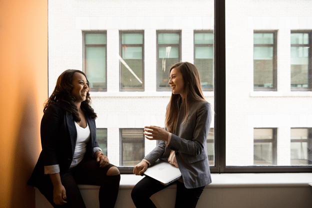 professional women laughing by window